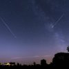 A star-filled purplish night sky, with two meteors streaking across